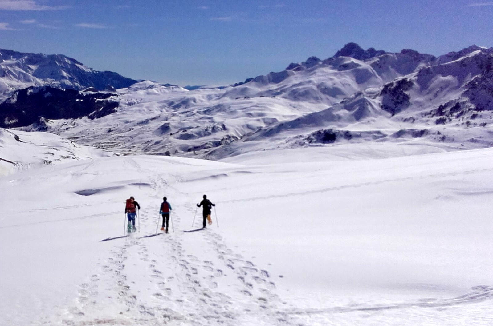 Three guests going downhill on snowshoes with nobody else in sight and huge wide open spaces on our Snowshoeing Holiday Spain with Aragon Active small group holidays