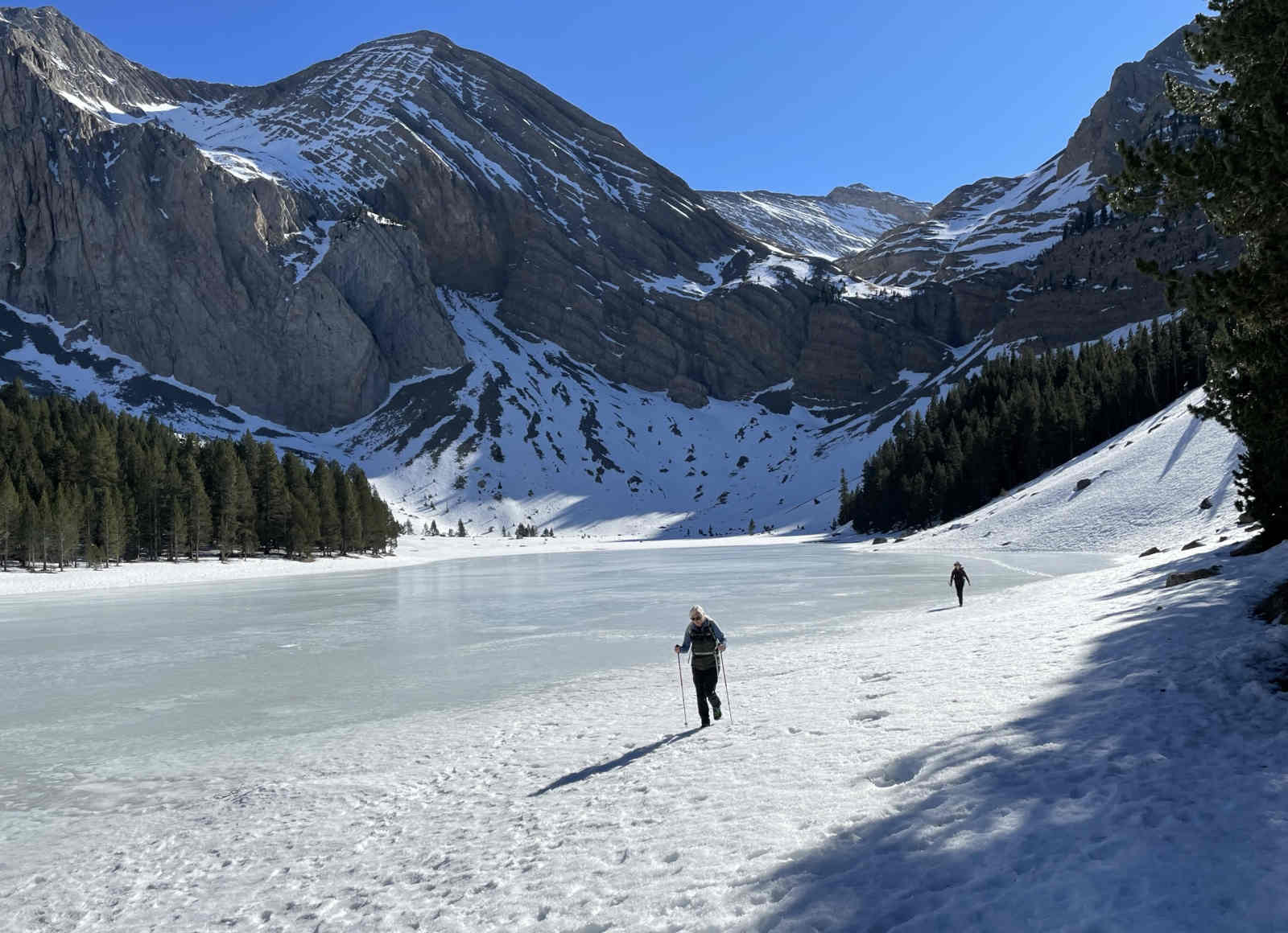 Two guests walking around a frozen lake with crampons in a Cirque on our Winter Walking and Snowshoeing Holiday Spain with Aragon Active small group holidays