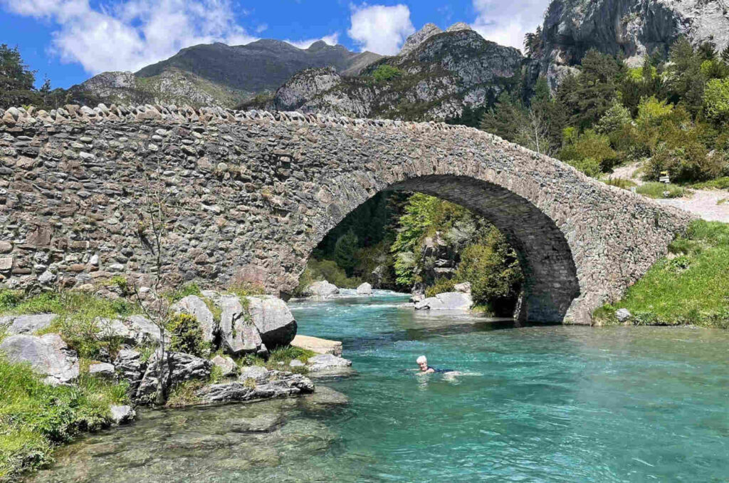 A students swimming by a medieval bridge in the Pyrenees on our Spanish Language Walking Holidays