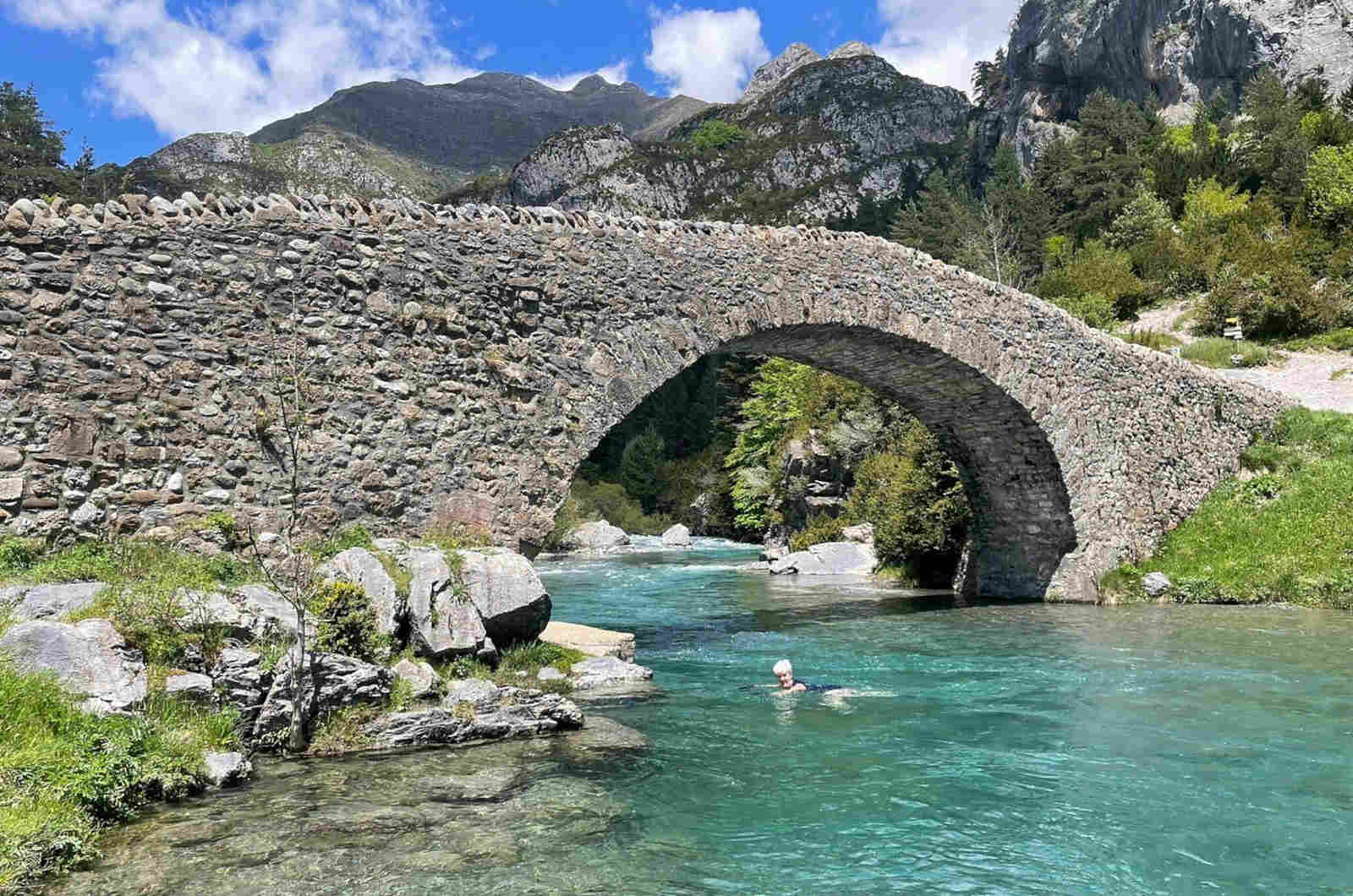 A student swimming by a medieval bridge in the Pyrenees on our Spanish Language Walking Holidays with Aragon Active small group holidays