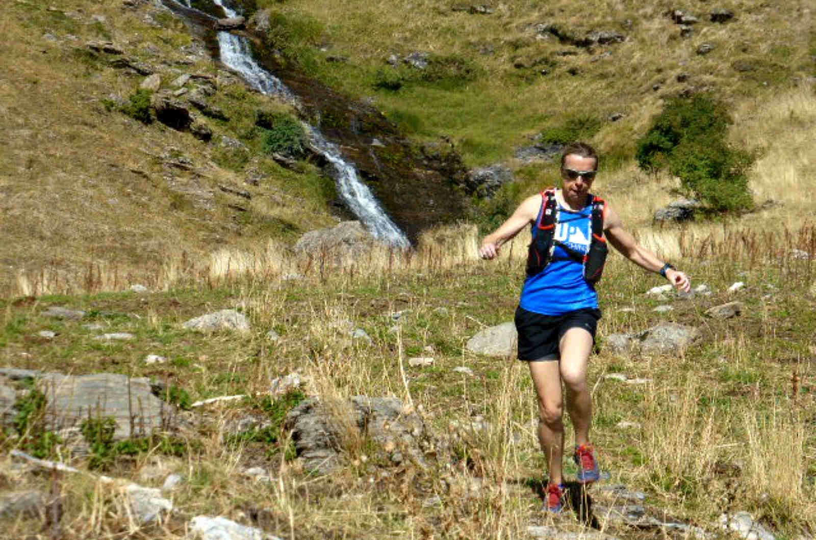 A female trail runner running down hill over rocky meadows in the Pyrenees on our Trail Running Holidays with Aragon Active small group holidays