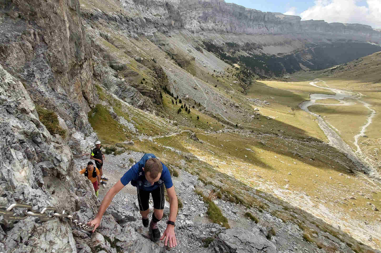 Three trail runners climbing up chains to reach another level in the Ordesa valley in the Pyrenees on our Trail Running Holidays with Aragon Active small group holidays